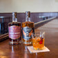 Five Saints Midnight Orchard Blackberry Plum Liqueur alongside Rare Pennsylvania Whiskey and a craft cocktail on a wooden bar