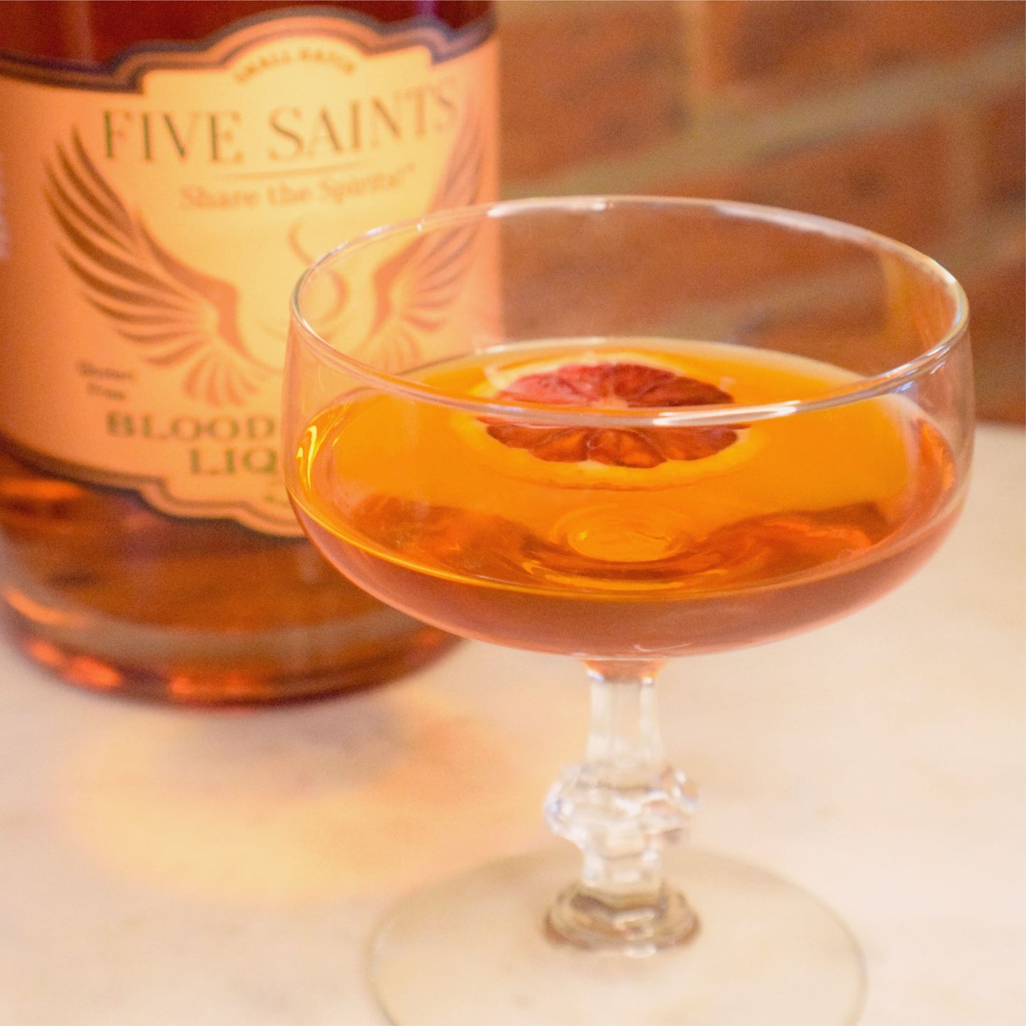 Blood orange martini in a coupe glass with dehydrated blood orange garnish, made with Five Saints Distilling Blood Orange Liqueur — craft cocktail-ready low-ABV spirit