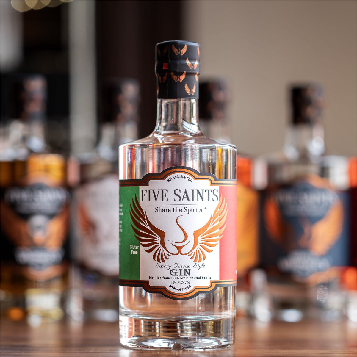 Five Saints Distilling Savory Tuscan Style Gin bottle, a small batch gluten-free gin distilled from 100% grain neutral spirits with Italian botanical herbs, with other spirits in the background