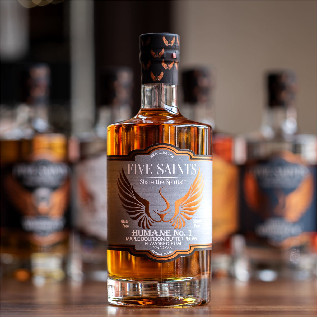 Five Saints Distilling Humane No.1 small batch Maple Bourbon Butter Pecan Flavored Rum bottle, gluten-free Pennsylvania craft spirit 750ml with other spirits in background