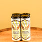 Four cans of Five Saints Rooftop Lemonade arranged side by side on a wooden surface against a warm yellow background.