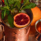 Blood Orange Moscow Mule cocktail made with Five Saints Distilling small batch vodka, served in copper mug with blood orange slice and fresh mint