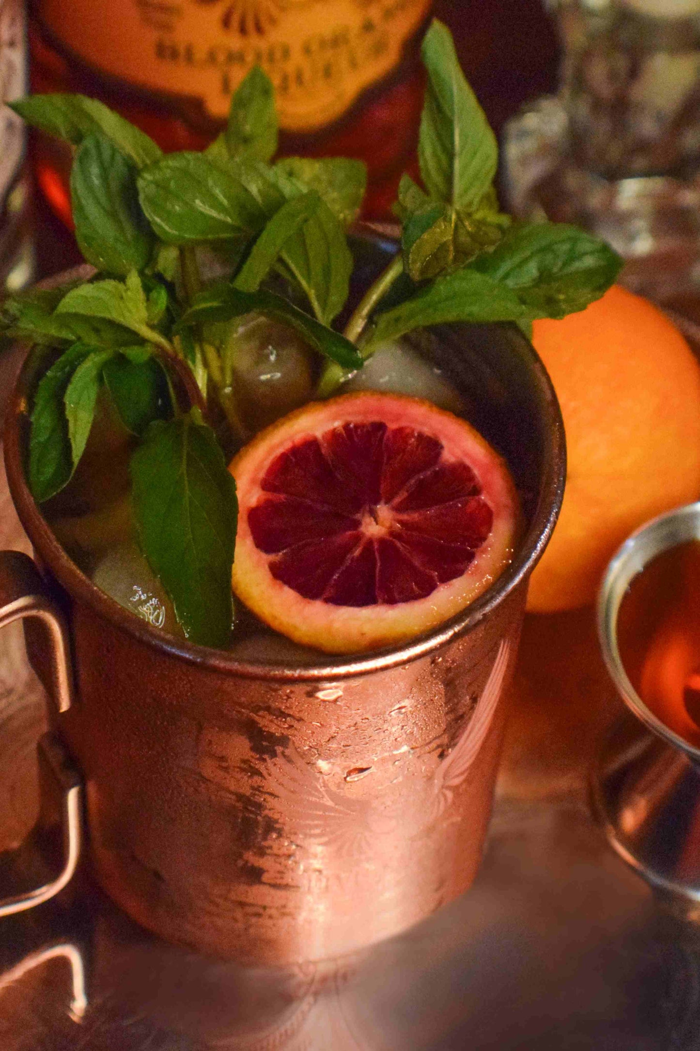 Blood Orange Moscow Mule cocktail in a copper mug garnished with a blood orange slice and fresh mint, made with Five Saints Distilling Vodka
